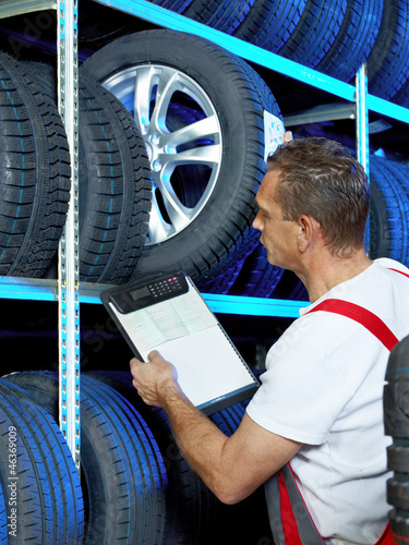 Photo: Car mechanic looking for a tire with registration certificate Car mechanic looking for a tire with registration certificate