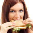 Cheerful woman eating sandwich with cheese