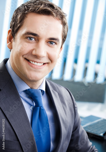 Photo: Portrait of smiling businessman at office Portrait of smiling businessman at office