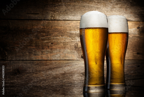 Photo: Two glass beer on wood background with copyspace Two glass beer on wood background with copyspace