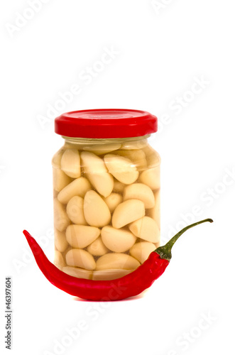 Photo: pickled garlic in glass jar with pepper on white pickled garlic in glass jar with pepper on white