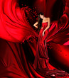 woman in red dress with long hair and hearts on red drapery