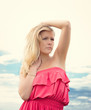 Young blond woman in white dress on background of the sky