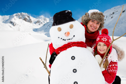 Photo: Winter fun, snowman and happy family Winter fun, snowman and happy family