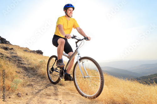Photo: Biker riding a mountain bike on a sunset Biker riding a mountain bike on a sunset