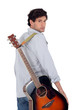 Man with acoustic guitar walking away from the camera