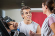 Instructor Looking At Female Client Exercising On Treadmill