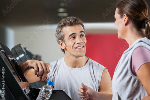 Photo: Instructor Looking At Female Client Exercising On Treadmill Instructor Looking At Female Client Exercising On Treadmill