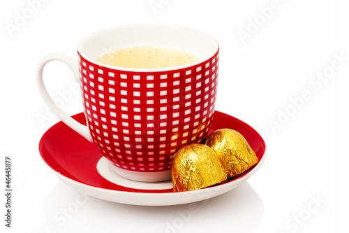 Photo: Cup of coffee with chocolate bonbons on white background Cup of coffee with chocolate bonbons on white background