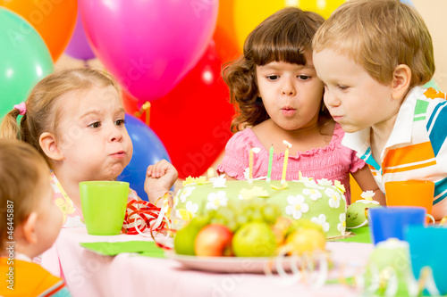 Photo: kids celebrating birthday party and blowing candles on cake kids celebrating birthday party and blowing candles on cake