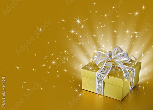 Photo: Golden surprise gift box or present with ribbon, bow, stars Golden surprise gift box or present with ribbon, bow, stars