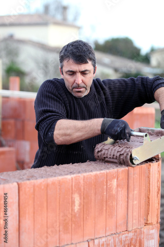 Photo: Mason pouring cement onto wall Mason pouring cement onto wall