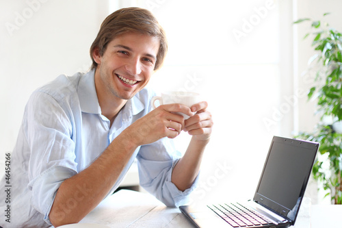 Photo: Young and handsome man drinking his coffee during a work break Young and handsome man drinking his coffee during a work break