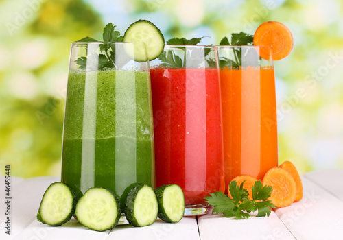 Photo: Fresh vegetable juices on wooden table, on green background Fresh vegetable juices on wooden table, on green background