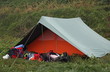 orange and green tent with many backpacks