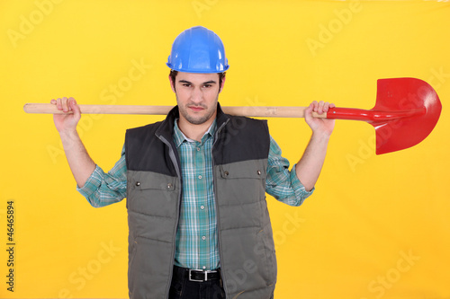 Photo: Scowling labourer carrying a shovel Scowling labourer carrying a shovel