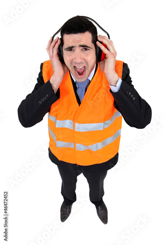 Photo: Man covering his ears with earmuffs Man covering his ears with earmuffs