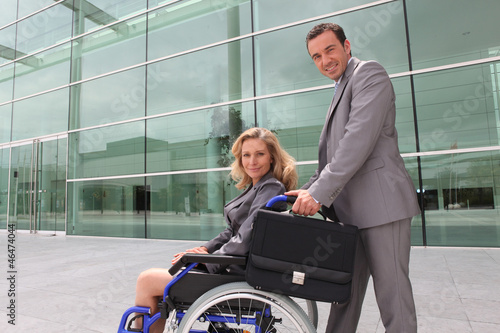 Photo: woman in a wheelchair and man helping woman in a wheelchair and man helping