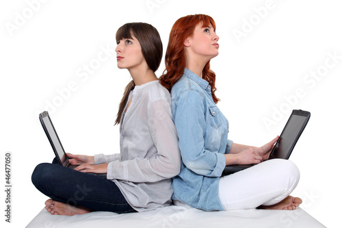 Photo: Two female friends sat together each using a laptop computer Two female friends sat together each using a laptop computer