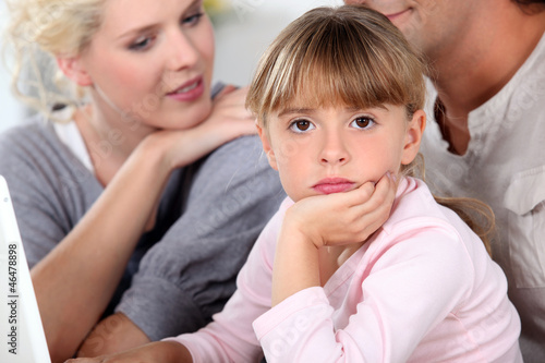 Photo: Bored little girl sat with her parents Bored little girl sat with her parents