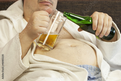 Photo: Man sitting on the couch with a beer in the hands of Man sitting on the couch with a beer in the hands of