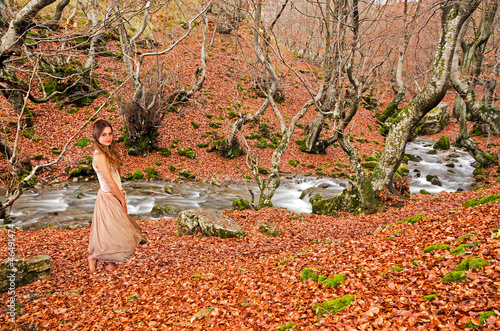 Photo: Beautiful girl walking barefoot in the wood in autumn Beautiful girl walking barefoot in the wood in autumn