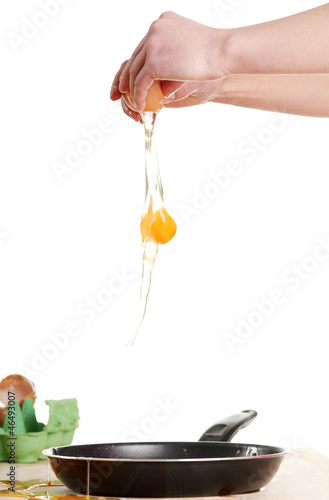 Photo: Hands breaking an egg. Hands breaking an egg.