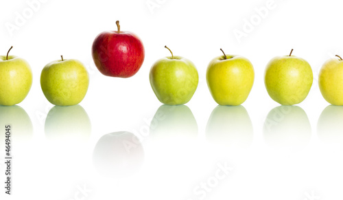 Photo: Red apple standing out from row of green apples. Red apple standing out from row of green apples.