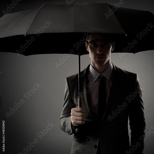 Photo: Businessman in costume holding black umbrella Businessman in costume holding black umbrella