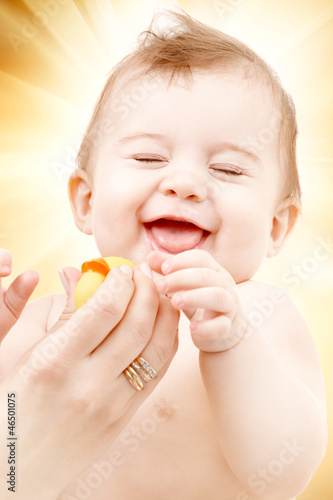Photo: laughing baby boy in mother hands with rubber duck laughing baby boy in mother hands with rubber duck