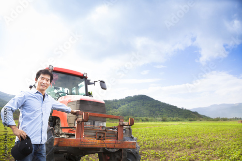 Photo: happy asian farmer with Old tractor on the grass field happy asian farmer with Old tractor on the grass field