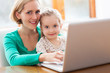 Mother and daughter using laptop at home