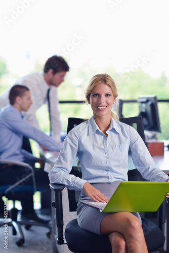 Photo: business woman with her staff in background at office business woman with her staff in background at office
