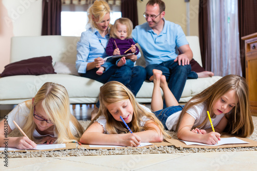 Photo: Family at home, the children coloring on floor Family at home, the children coloring on floor