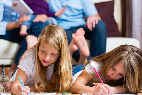 Photo: Family at home, the children coloring on floor Family at home, the children coloring on floor