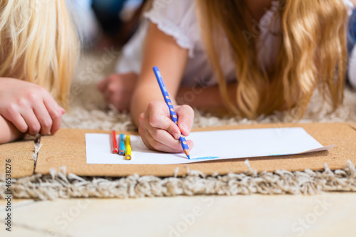Photo: Family at home, the children coloring on floor Family at home, the children coloring on floor