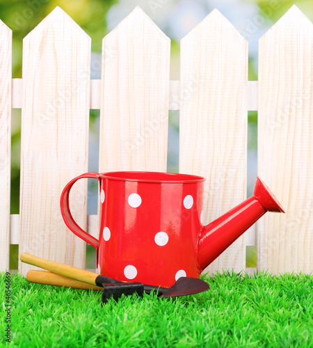Photo: gardening tools on green grass on wooden fence background gardening tools on green grass on wooden fence background