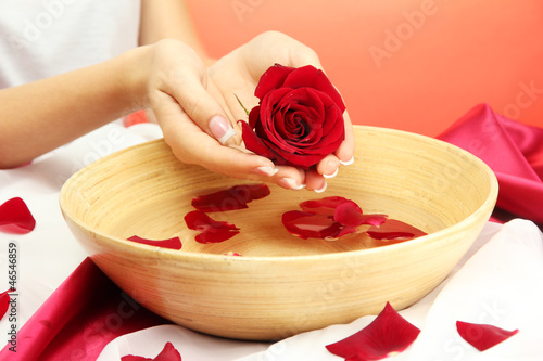Photo: woman hands with wooden bowl of water with petals, woman hands with wooden bowl of water with petals,