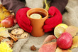 hands holding cup of hot drink and autumn leaves,