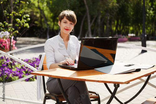Photo: Young businesswoman with laptop at a sidewalk cafe Young businesswoman with laptop at a sidewalk cafe