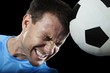 Soccer player heading the soccer ball against black background