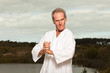 Photo: Senior spiritual man dressed in white.Exercising outdoors. Senior spiritual man dressed in white.Exercising outdoors.