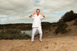Photo: Senior spiritual man dressed in white.Exercising outdoors. Senior spiritual man dressed in white.Exercising outdoors.