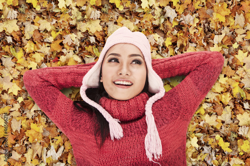 Photo: Happy woman laying on Autumn leaves Happy woman laying on Autumn leaves