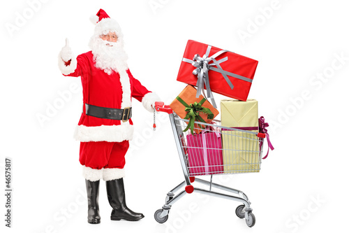 Photo: Santa Claus holding a cart full of gifts and giving a thumb up Santa Claus holding a cart full of gifts and giving a thumb up