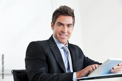 Photo: Young Businessman Using Digital Tablet In Office Young Businessman Using Digital Tablet In Office