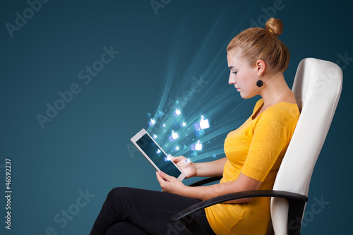 Photo: Young woman looking at modern tablet with abstract lights and so Young woman looking at modern tablet with abstract lights and so
