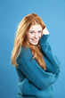 Cute female redhead wearing blue jumper on blue background