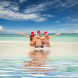Photo: Happy friends in santa hats on the beach. Christmas vacation Happy friends in santa hats on the beach. Christmas vacation