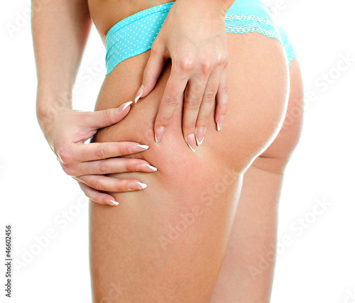 Photo: Young woman folding skin on her hips with both hands. Young woman folding skin on her hips with both hands.